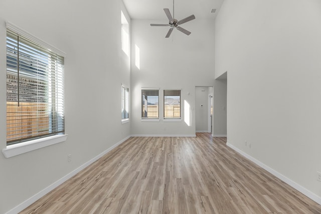 21624 Alberta Forest Cir, Magnolia, TX 77355 - unfurnished living room featuring light wood finished floors, a high ceiling, baseboards, and ceiling fan