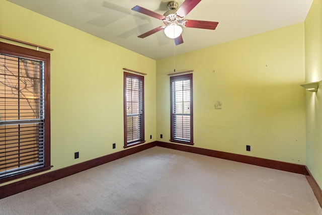 spare room with ceiling fan, baseboards, and carpet