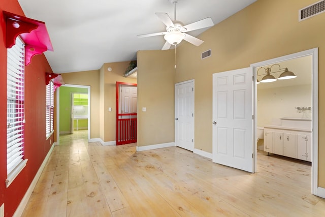 unfurnished living room with light wood finished floors, visible vents, a ceiling fan, and lofted ceiling