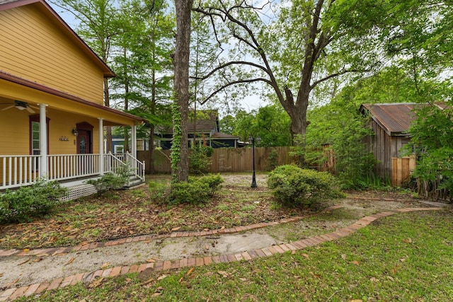view of yard featuring a porch, fence, and ceiling fan