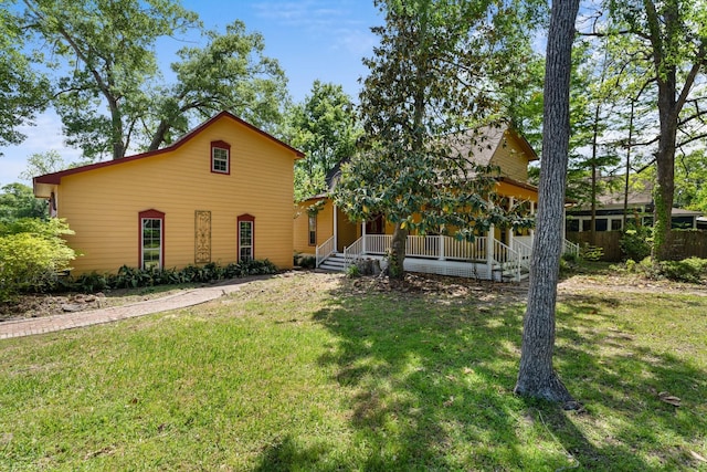 rear view of house featuring a yard and covered porch