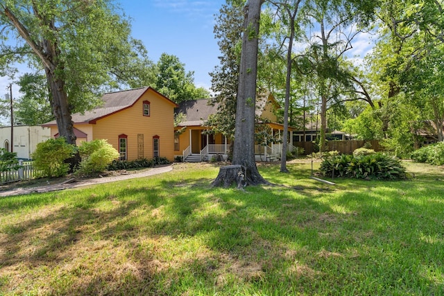 back of house featuring fence, covered porch, and a yard