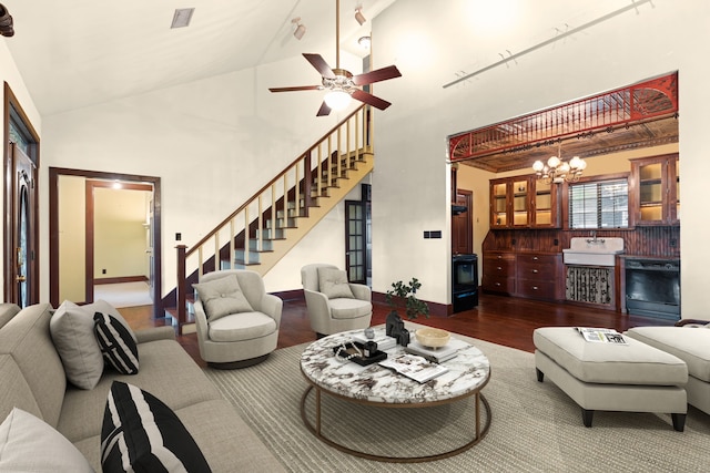 living area featuring baseboards, visible vents, ceiling fan with notable chandelier, wood finished floors, and stairs