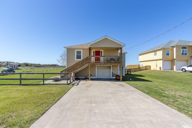 2027 103rd St, Galveston, TX 77554 - raised beach house with a front yard, fence, stairs, an attached garage, and concrete driveway
