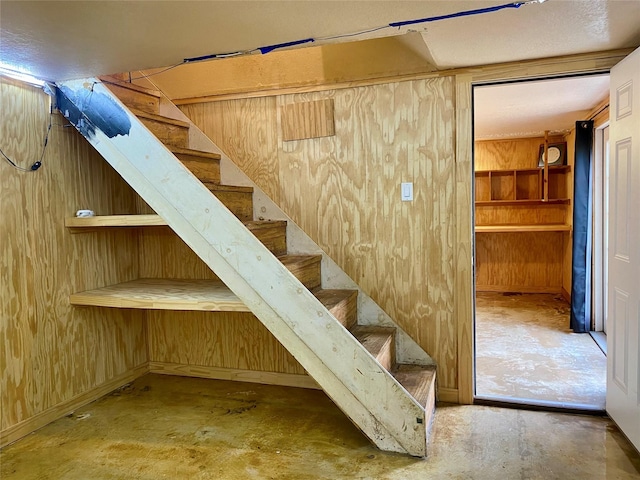2027 103rd St, Galveston, TX 77554 - stairway featuring wooden walls and unfinished concrete flooring
