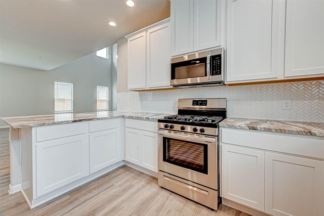 kitchen with tasteful backsplash, light wood-type flooring, a peninsula, white cabinets, and appliances with stainless steel finishes