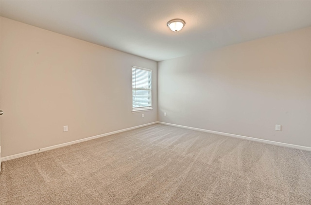 carpeted spare room featuring baseboards