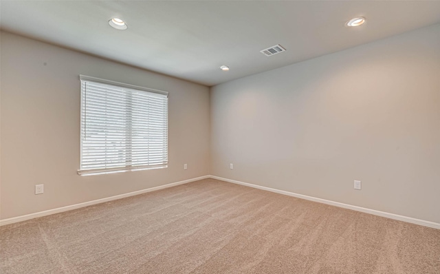 unfurnished room featuring carpet, visible vents, and baseboards