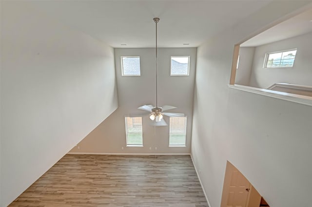 interior space featuring baseboards, a ceiling fan, plenty of natural light, and wood finished floors