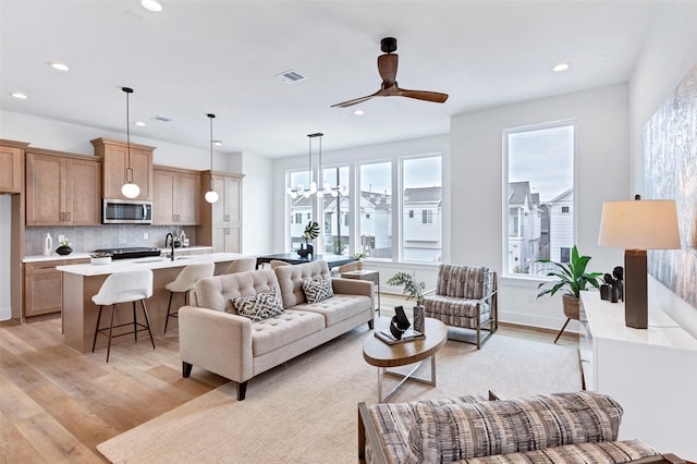 living area with light wood-style flooring, ceiling fan with notable chandelier, visible vents, and recessed lighting
