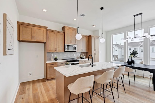 kitchen with tasteful backsplash, light wood-type flooring, visible vents, appliances with stainless steel finishes, and a sink