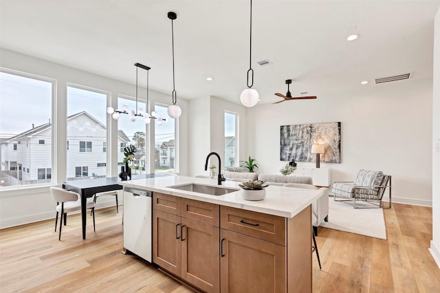 kitchen with light wood-type flooring, open floor plan, a center island with sink, dishwasher, and a sink