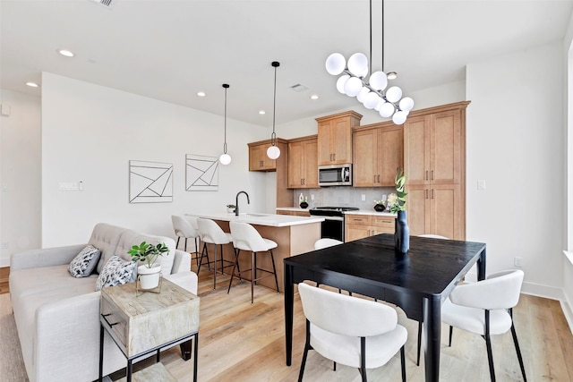 kitchen with tasteful backsplash, appliances with stainless steel finishes, light countertops, a sink, and light wood finished floors
