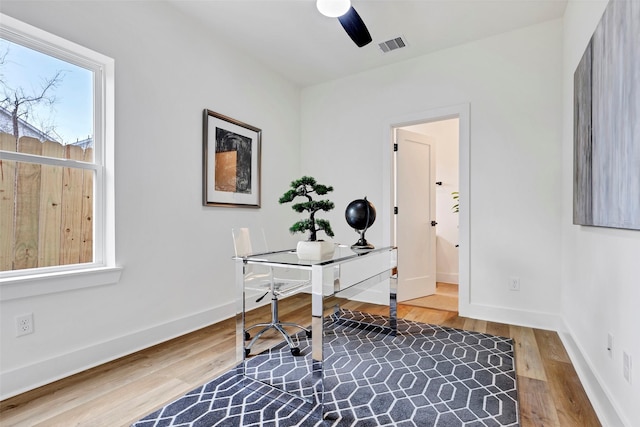 home office with visible vents, ceiling fan, baseboards, and wood finished floors