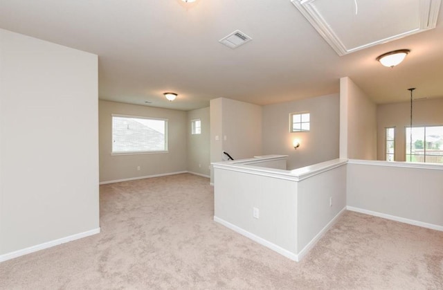 unfurnished room featuring baseboards, light carpet, plenty of natural light, attic access, and visible vents