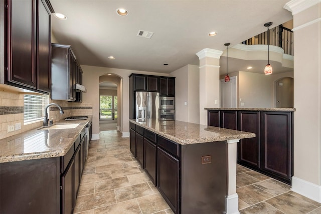1715 Laremont Bend Dr, Spring, TX 77386 - kitchen with a sink, appliances with stainless steel finishes, arched walkways, dark brown cabinetry, and recessed lighting