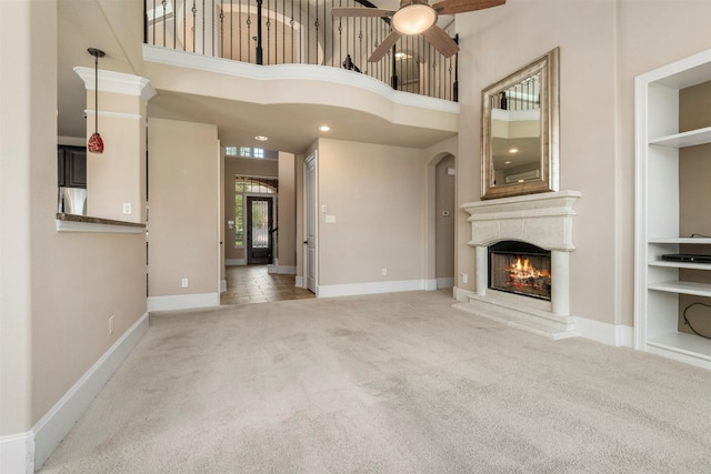 1715 Laremont Bend Dr, Spring, TX 77386 - unfurnished living room with ceiling fan, carpet flooring, a lit fireplace, a high ceiling, and baseboards