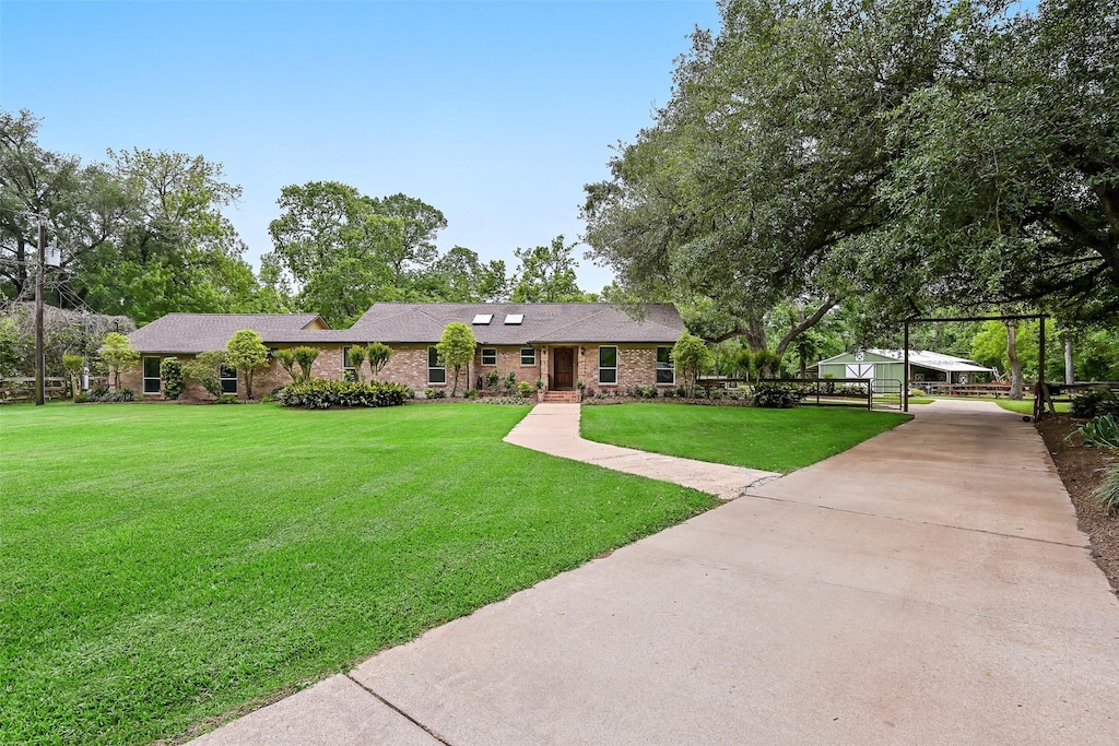 single story home featuring a front yard, brick siding, and driveway