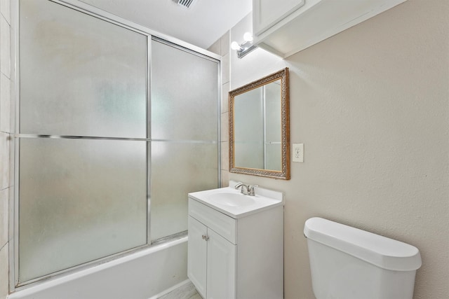 bathroom featuring toilet, vanity, and bath / shower combo with glass door