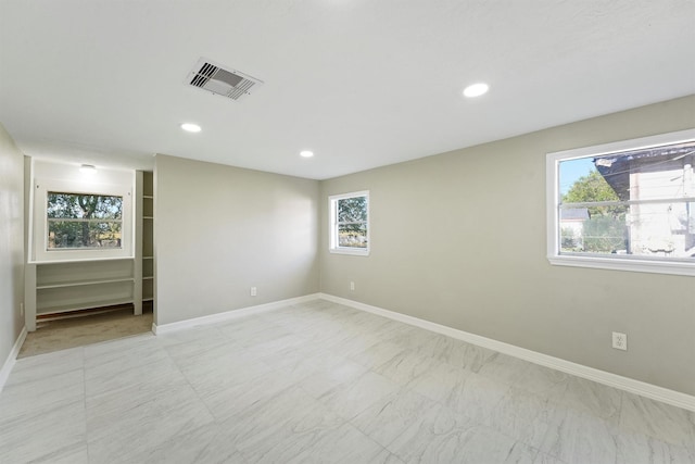empty room featuring a healthy amount of sunlight, baseboards, visible vents, and recessed lighting