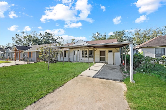 view of front of home with concrete driveway, an attached carport, fence, and a front lawn