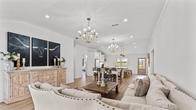 living area with visible vents, light wood-type flooring, an inviting chandelier, and crown molding