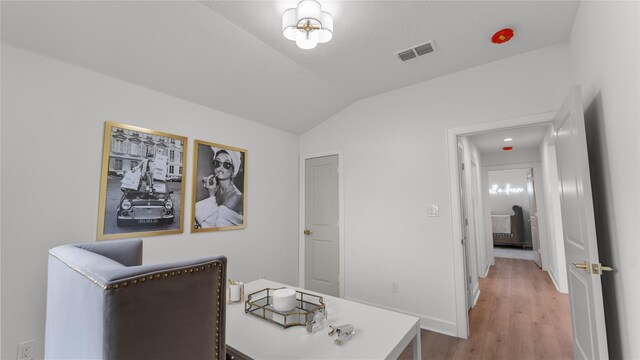 home office featuring wood finished floors, baseboards, vaulted ceiling, and visible vents