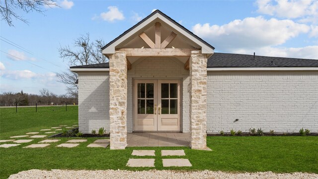 entrance to property with french doors, brick siding, and a yard