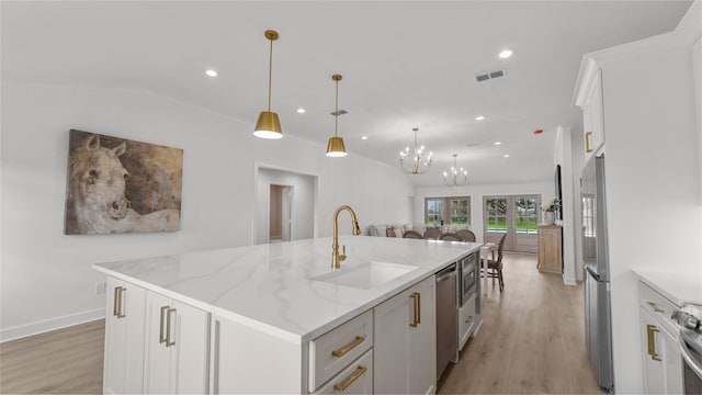 kitchen with light wood-style flooring, a center island with sink, a sink, and visible vents