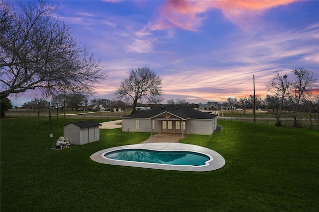 pool with a storage shed, a lawn, a fenced backyard, an outdoor structure, and french doors