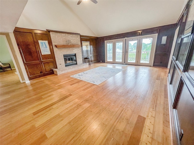 3203 Bayou Dr, La Porte, TX 77571 - unfurnished living room featuring light wood-type flooring, a ceiling fan, high vaulted ceiling, a decorative wall, and a fireplace