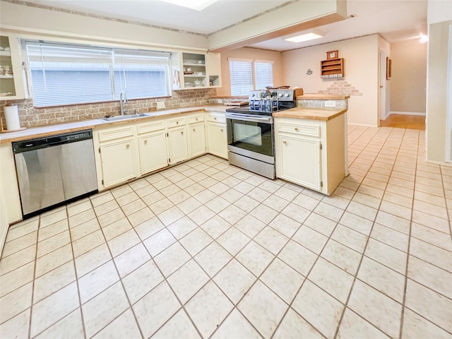 3203 Bayou Dr, La Porte, TX 77571 - kitchen with appliances with stainless steel finishes, a sink, decorative backsplash, light tile patterned floors, and a peninsula