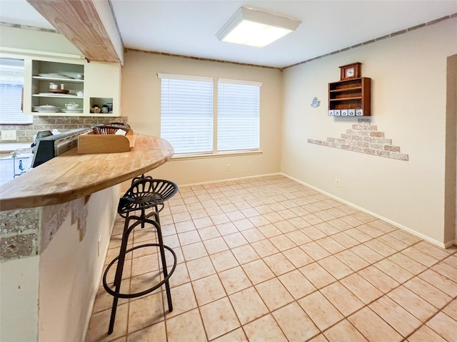 3203 Bayou Dr, La Porte, TX 77571 - kitchen with light tile patterned floors, open shelves, a breakfast bar, and baseboards