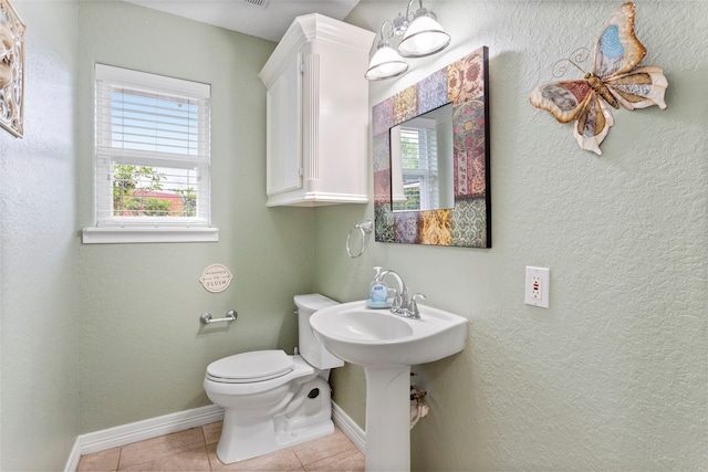 half bathroom with toilet, baseboards, and plenty of natural light