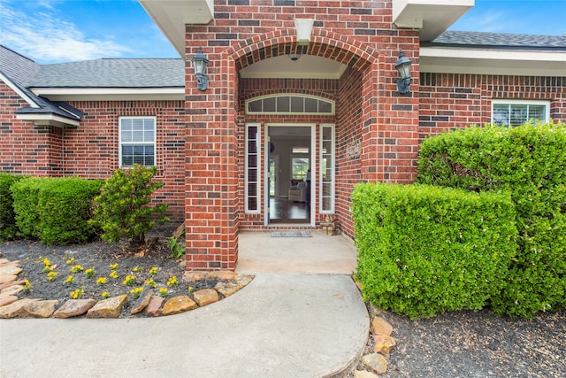 entrance to property with brick siding and roof with shingles