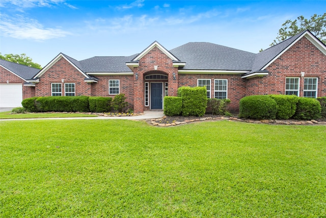 view of front of home with roof with shingles, a front lawn, and brick siding