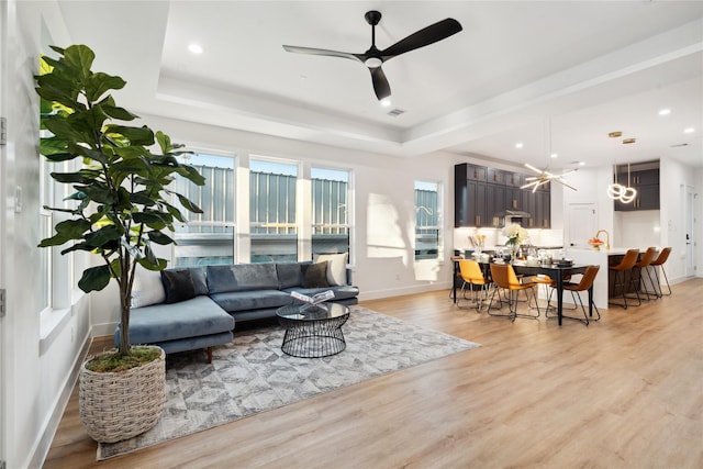 4323 Rogers St, Houston, TX 77022 - living room with a raised ceiling, ceiling fan, baseboards, and light wood-style flooring