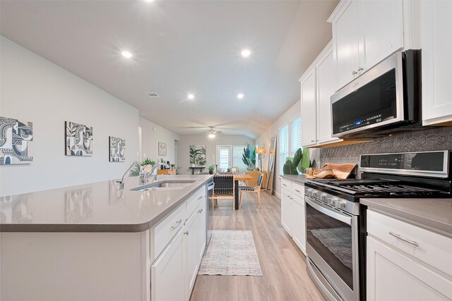 24603 Dover Bend Way, Richmond, TX 77406 - kitchen featuring stainless steel appliances, a sink, light wood-style flooring, ceiling fan, and decorative backsplash