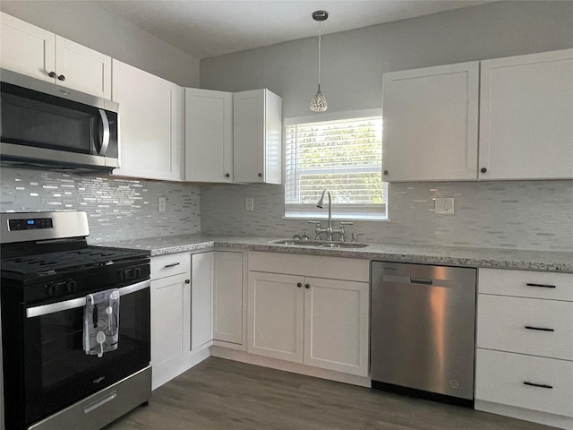 1701 40th St, Galveston, TX 77550 - kitchen featuring stainless steel appliances, a sink, dark wood-style flooring, white cabinetry, and decorative backsplash