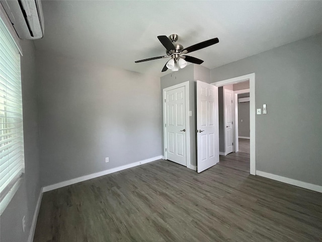 1701 40th St, Galveston, TX 77550 - unfurnished bedroom featuring a wall unit AC, baseboards, dark wood-style flooring, and a ceiling fan