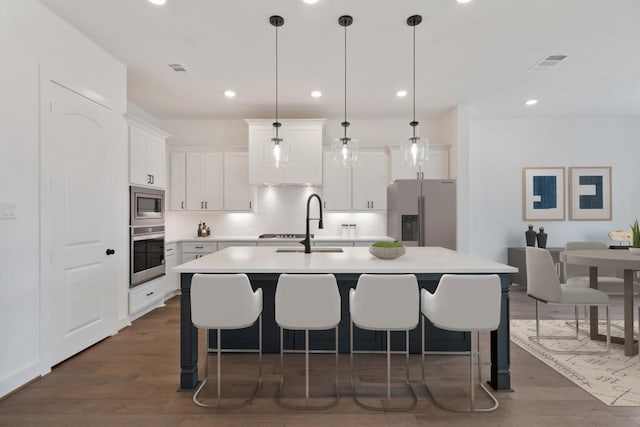 kitchen featuring tasteful backsplash, visible vents, light countertops, appliances with stainless steel finishes, and dark wood-style floors