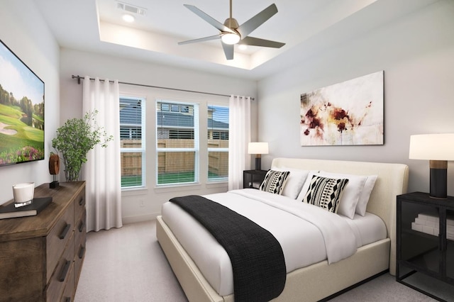 bedroom featuring baseboards, a ceiling fan, visible vents, a raised ceiling, and light colored carpet