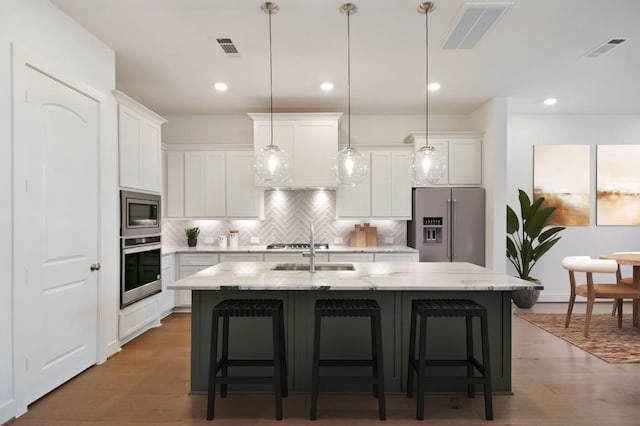 kitchen with a center island with sink, visible vents, and stainless steel appliances