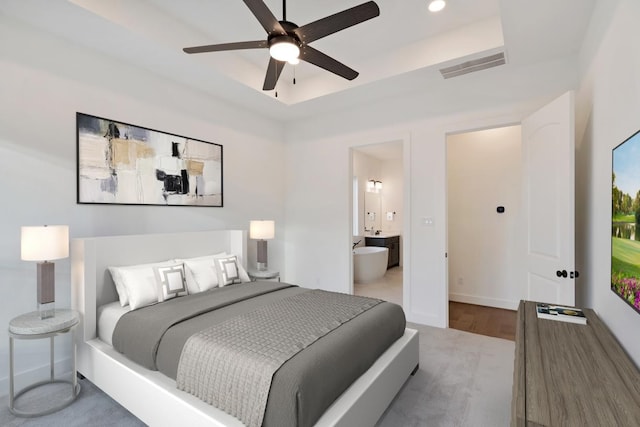 bedroom featuring baseboards, recessed lighting, ensuite bathroom, visible vents, and a tray ceiling
