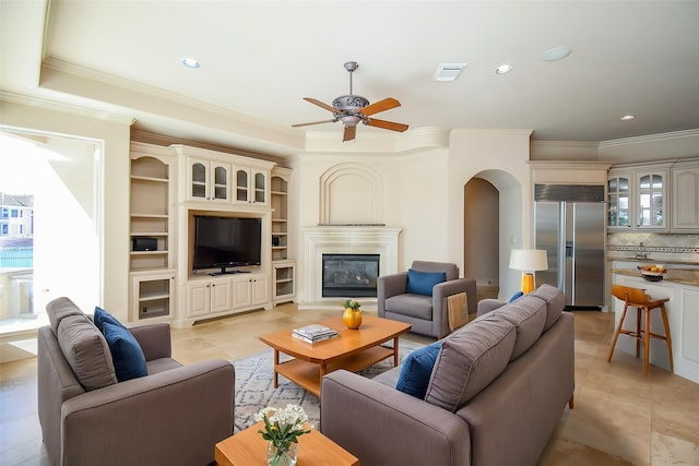 2 Royal Hampton Ct, Sugar Land, TX 77479 - living area featuring visible vents, a ceiling fan, ornamental molding, arched walkways, and a glass covered fireplace