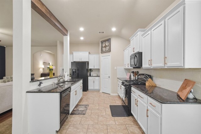 kitchen with arched walkways, a sink, black appliances, white cabinetry, and decorative backsplash