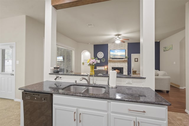 kitchen featuring a fireplace, dark stone countertops, dishwasher, a sink, and open floor plan