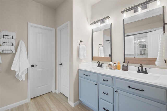 bathroom featuring a sink, baseboards, double vanity, and wood finished floors