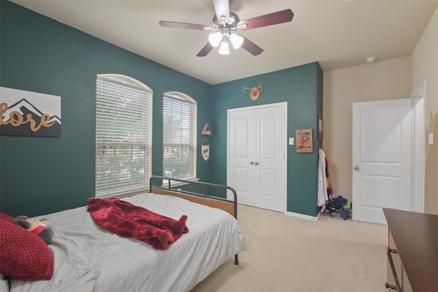 bedroom with light carpet, a closet, ceiling fan, and baseboards