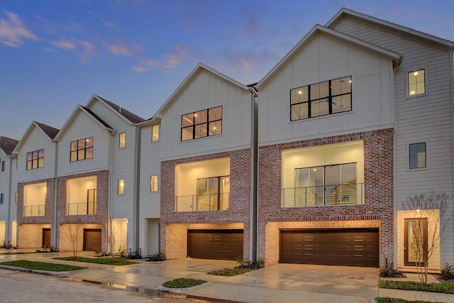 multi unit property with brick siding, a garage, and driveway